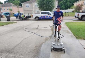 Man operating a commercial pressure washer on a driveway, showcasing driveway cleaning services in Ocala, Florida.