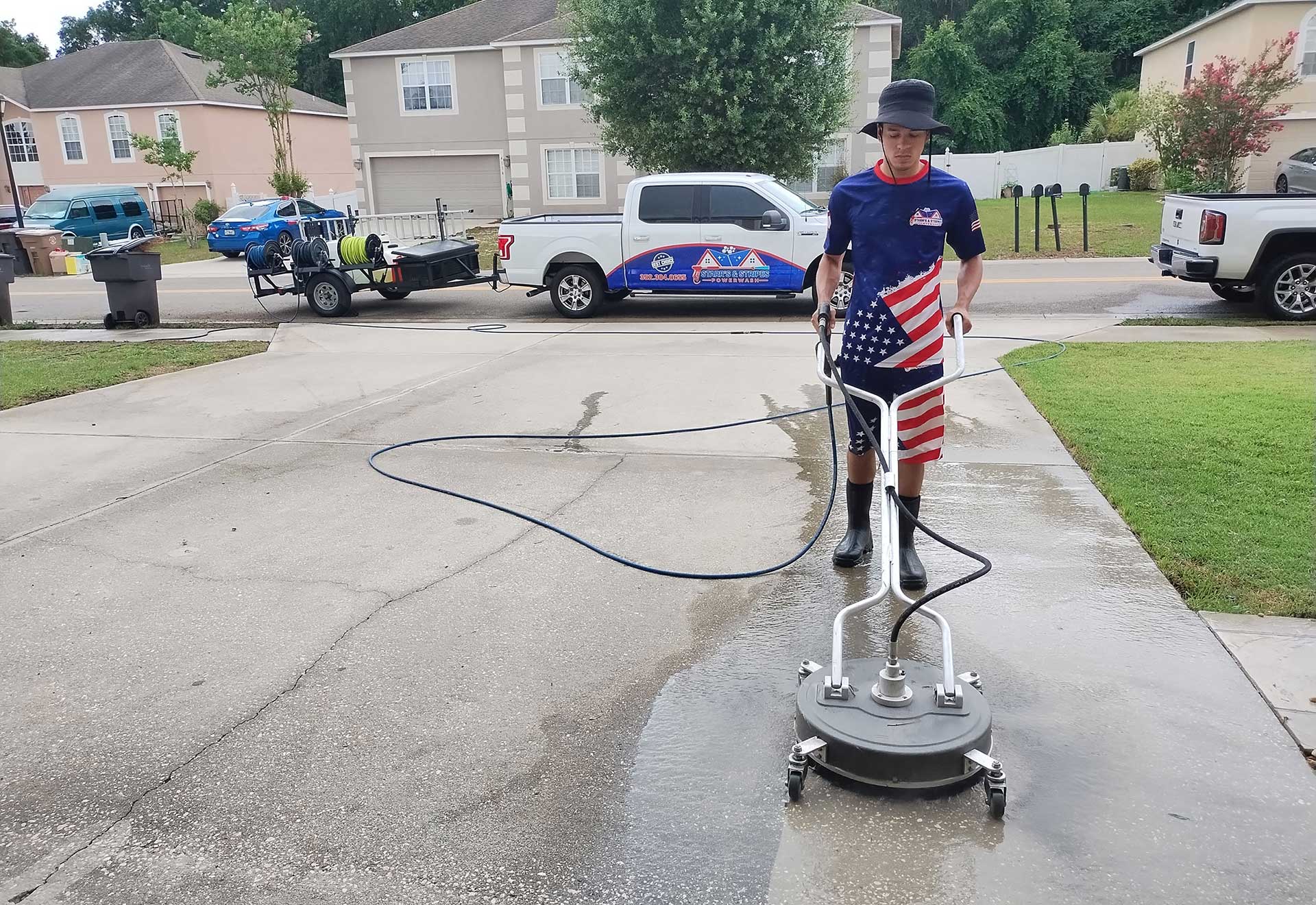 Man in patriotic attire using a pressure washer on a driveway, showcasing professional driveway cleaning services in Ocala, FL.