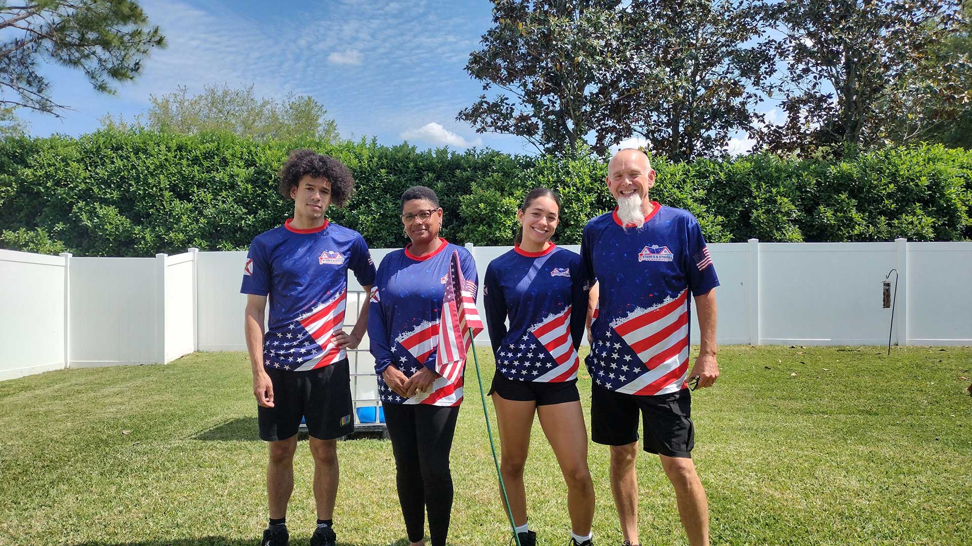 The Starr’s & Stripes PowerWash team, including Randy and Matthew, standing in a backyard wearing patriotic blue and red company jerseys.