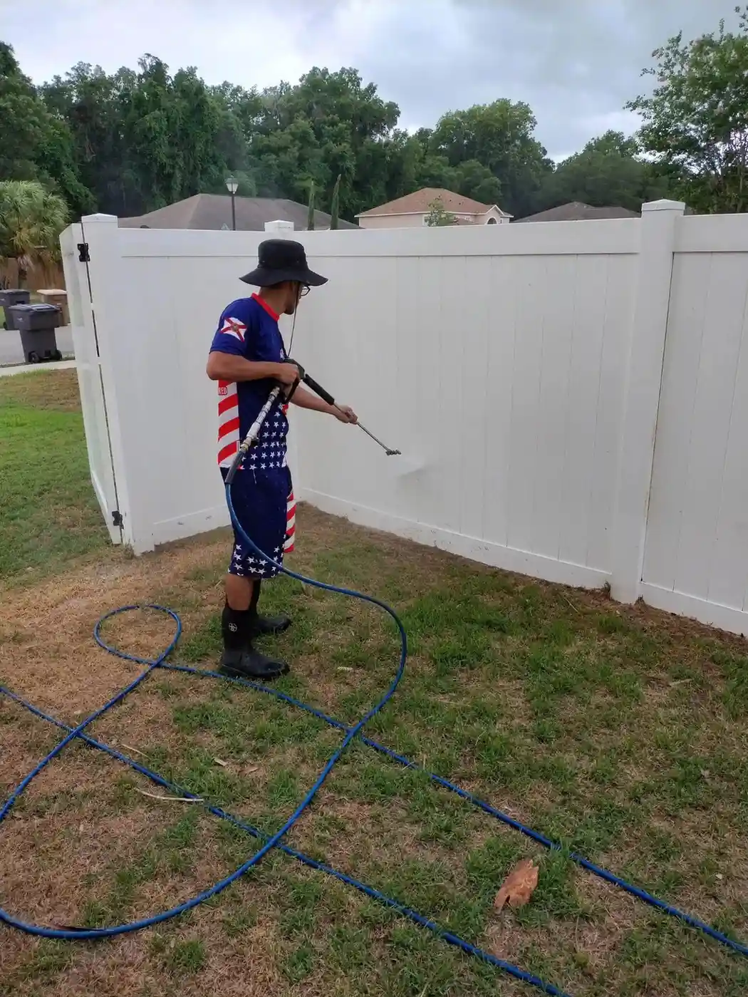 Man-pressure-washing-a-white-vinyl-fence