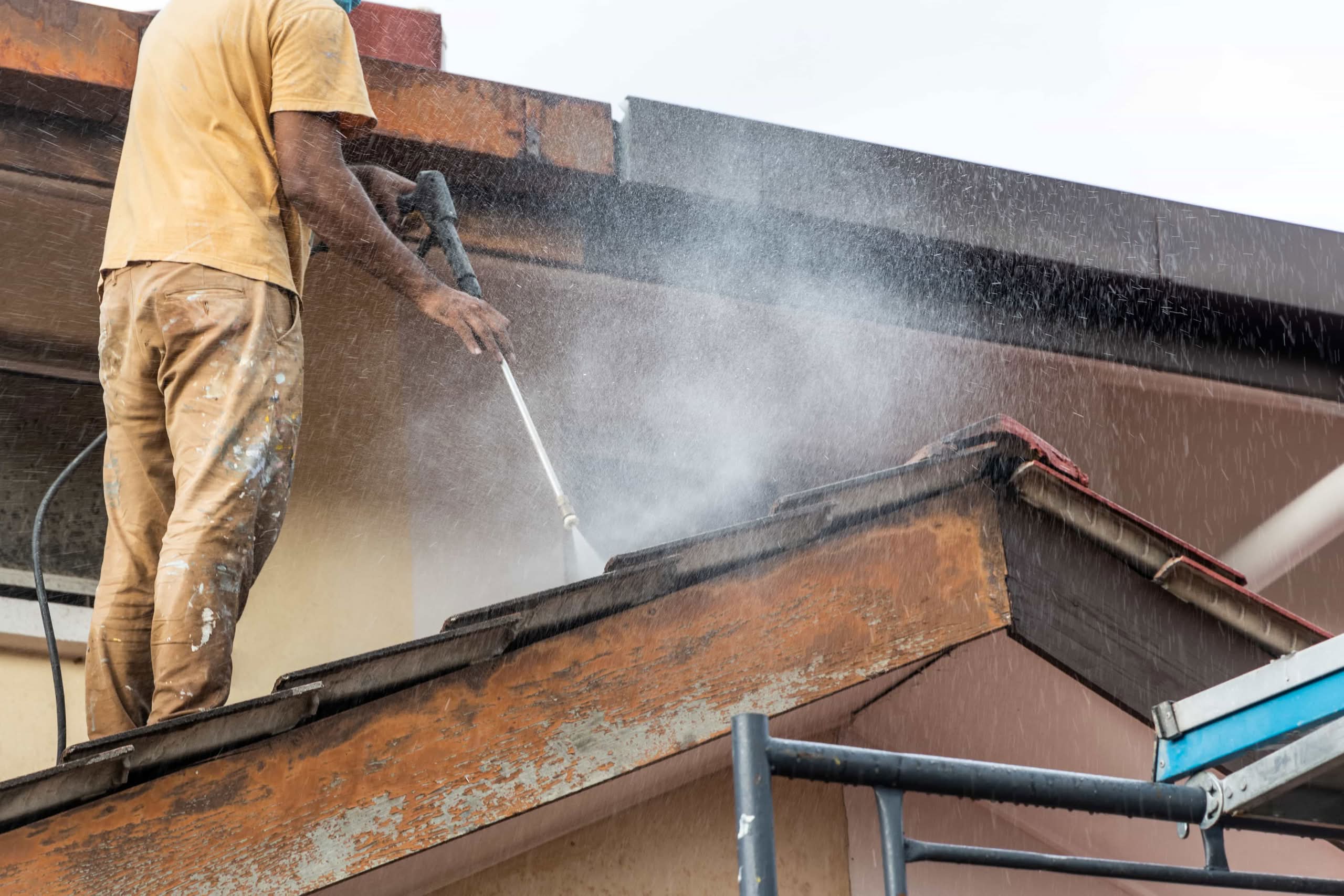Prevent Costly Damage: Gutter Cleaning Power Washing (2026) 1 A professional worker using a high-pressure water jet spray gun to clean a residential roof in Houston, TX, removing dirt and debris and gutter cleaning power washing.